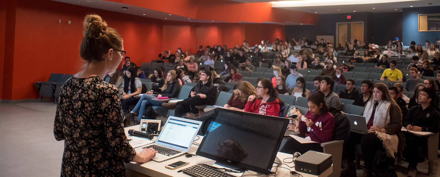 Queen’s professor standing at the front of a lecture hall with students