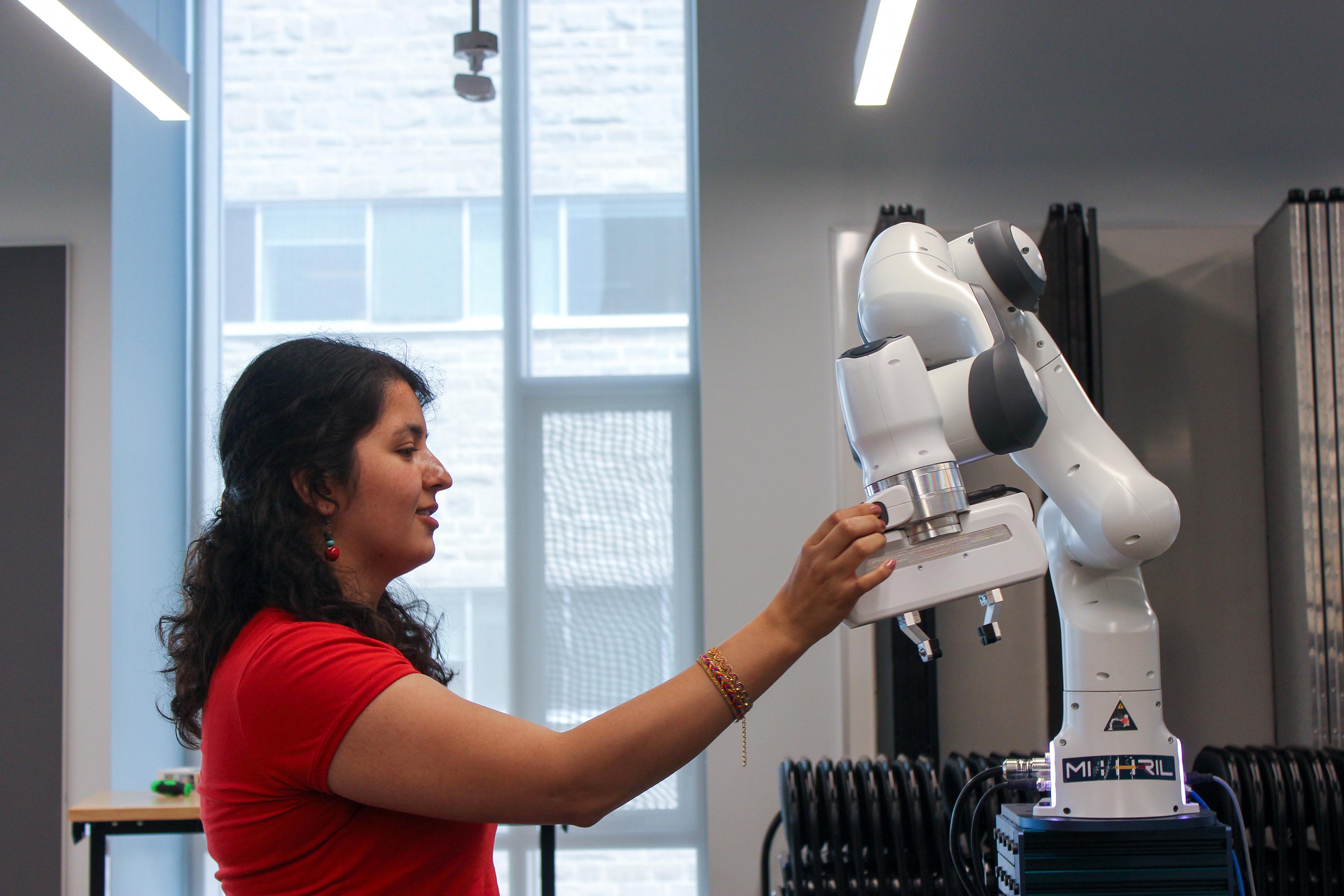 Student adjusting robotic arm in Ingenuity Labs 