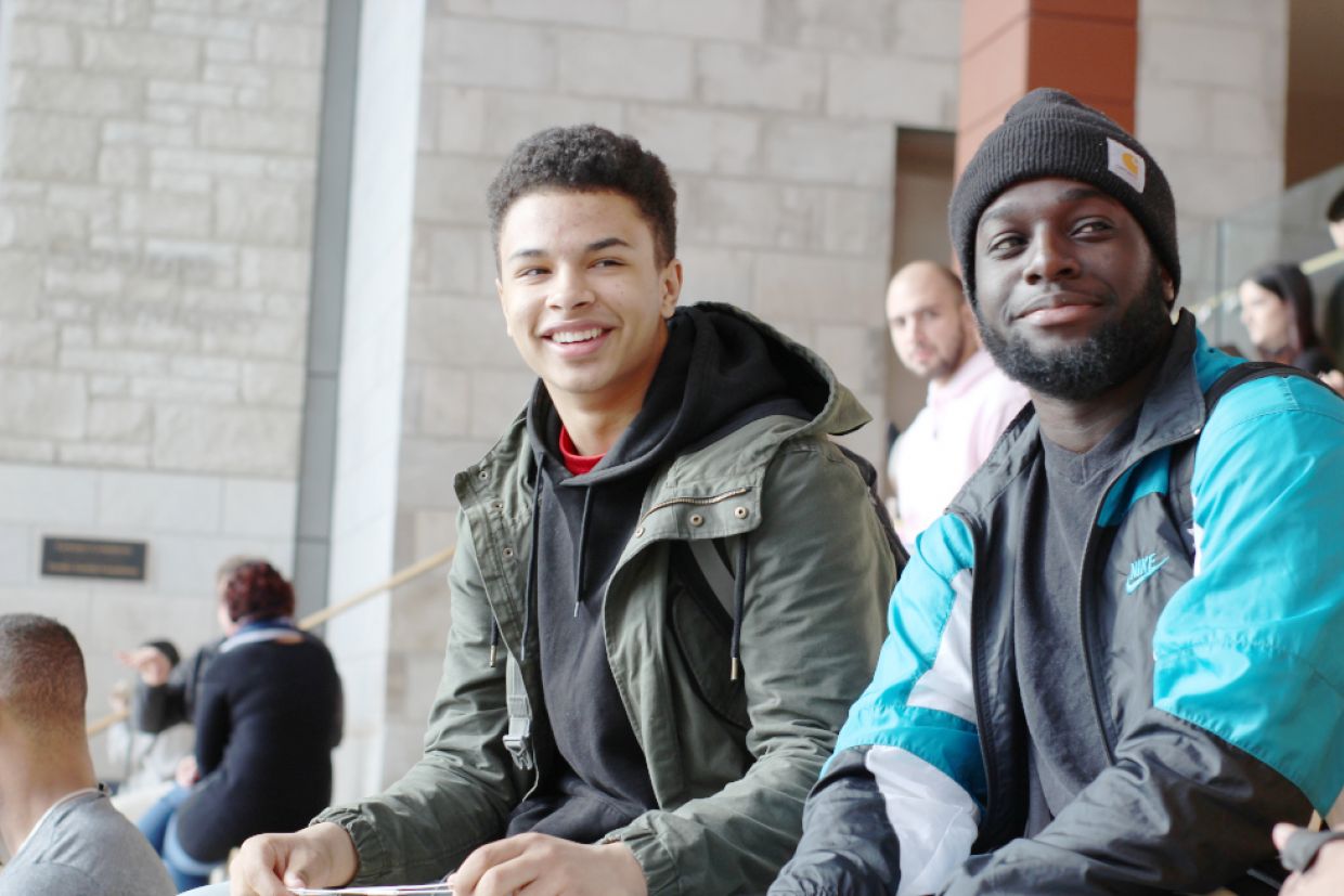 Two students sit in Goodes Hall and smile