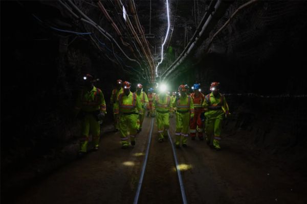A group of people wearing high-visibility clothing walk down a tunnel.