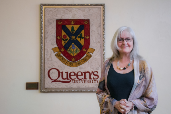 Dr. Margaret Gibson stands in front of the Queen's Crest.