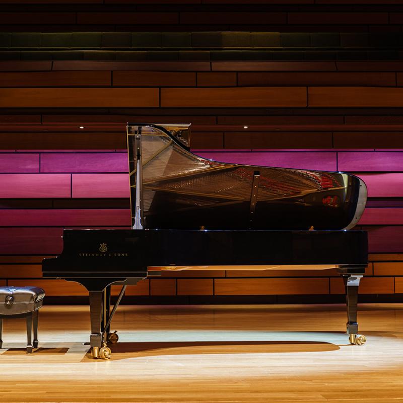 A side view of a Steinway piano on a stage.