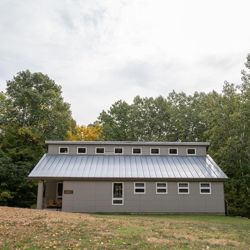 Building with a metal roof sits on a clearing in the woods