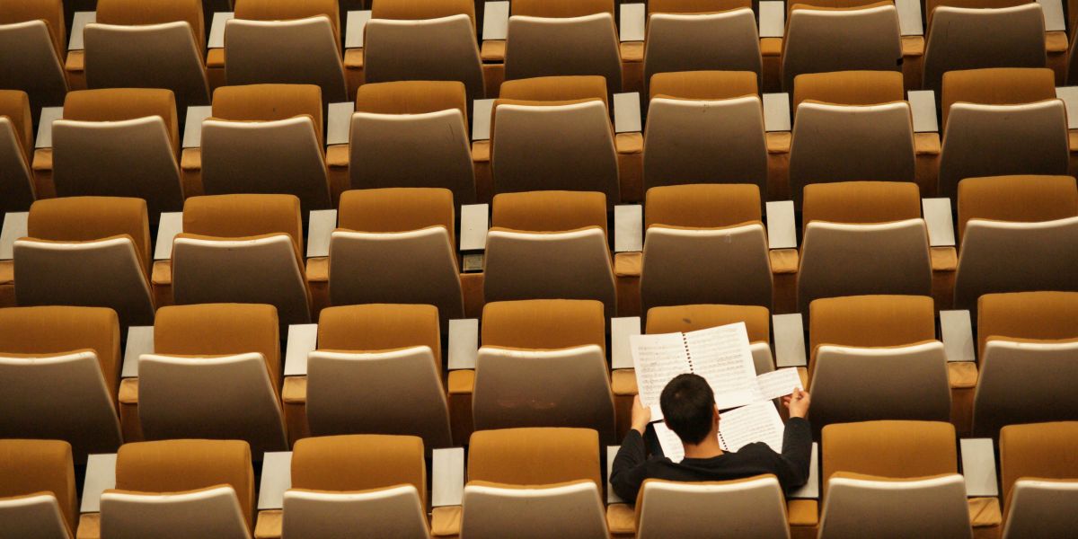 One student studying in a classroom full of empty chairs