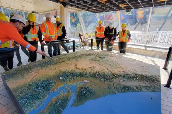 Students standing around a table in hard hats.