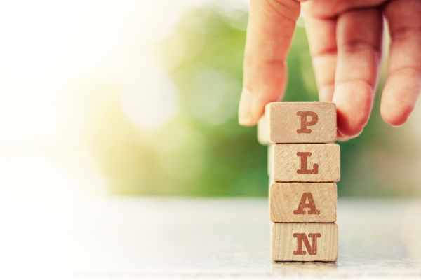 A hand placing a stack of blocks that says PLAN