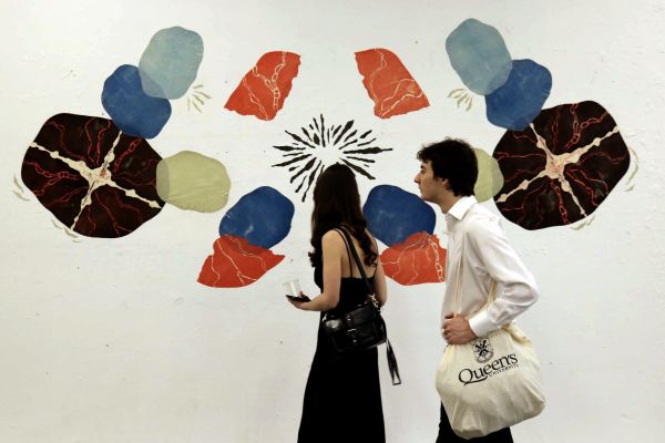 Two people walking past a paintaing.
