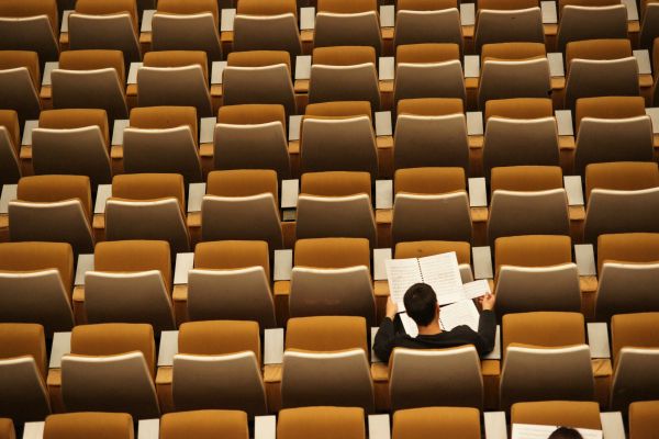 One student studying in a classroom full of empty chairs