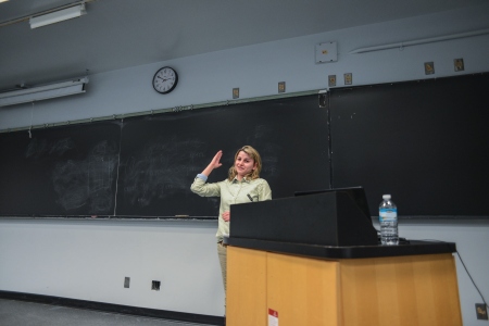 A person presenting in front of a chalkboard