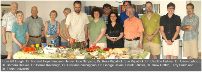 Faculty members standing behind a table full of food