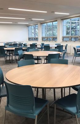 round tables with blue chairs surrounding them with white walls behind