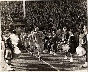 [photo of Queen's Golden Gaels football team running onto the field in 1955]