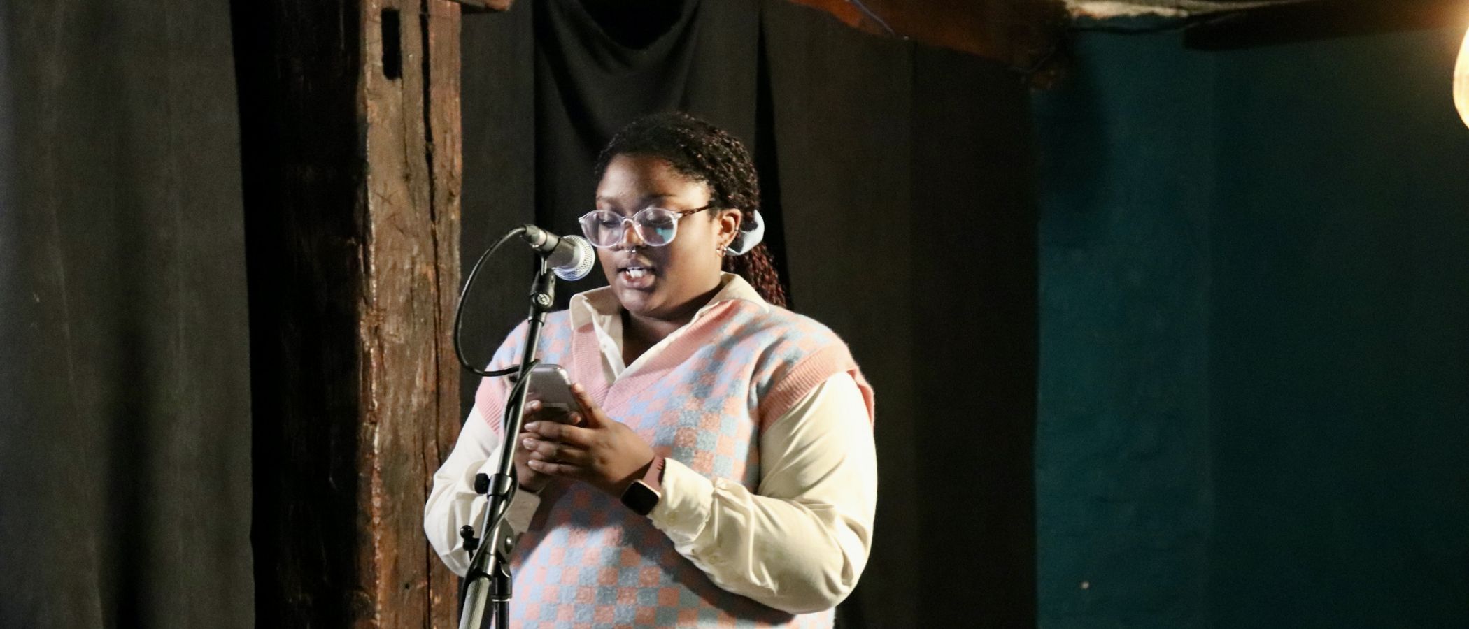 photo of grad student on stage reading their poetry 