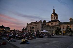 Many people sitting in the square behind Kingston City Hall.