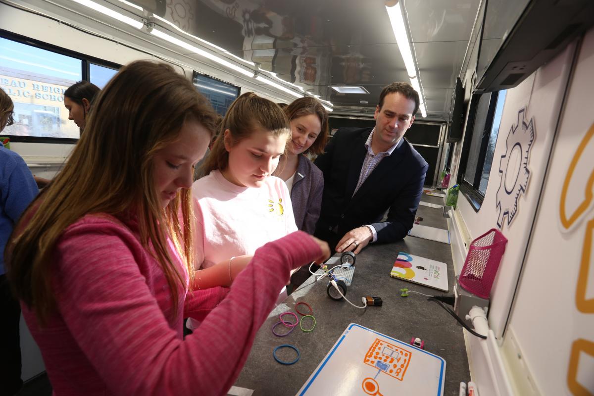 Kingston and the Islands MP Mark Gerretsen and local grade school students try their hand at some robotics experiments in the Queen's Tinker Trailer. (University Communications)