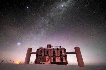 Credit: Martin Wolf, IceCube/NSF – Front view of the IceCube Lab at twilight, with a starry sky showing a glimpse of the Milky Way overhead and sunlight lingering on the horizon. 