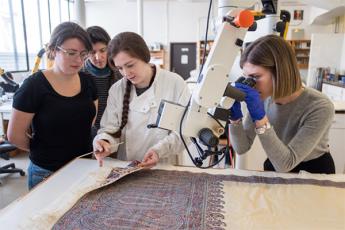 [Isabel Bader Fellow and Graduate Intern in Textile Conservation and Research analyze garments from the Queen’s Collection of Canadian Dress.]