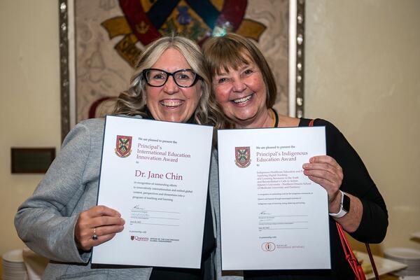 two professors smiling with their awards