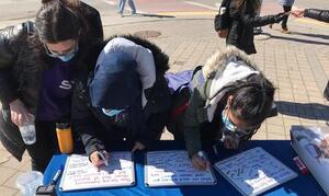 Students writing on banner