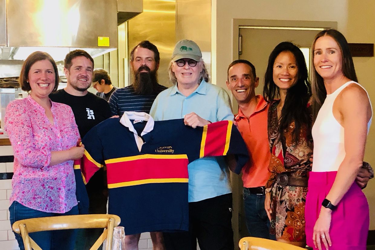 A group of alumni gathered for a photo with a Queen's rugby shirt