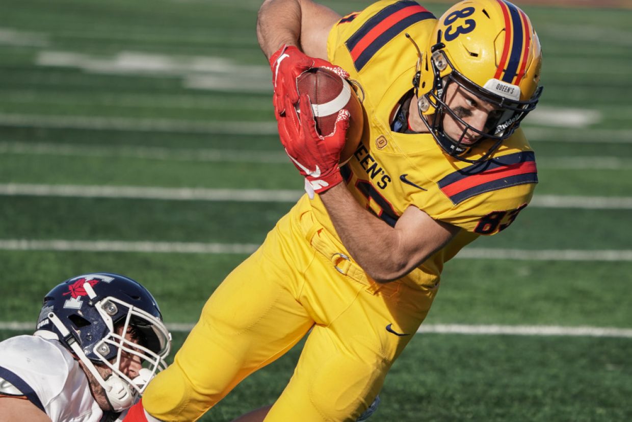 A Queen's Gael holds the football while being tackled. 