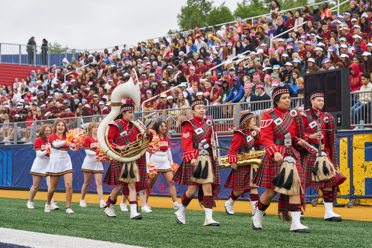 Queen's Bands musicians march by the stands in Richardson Stadium