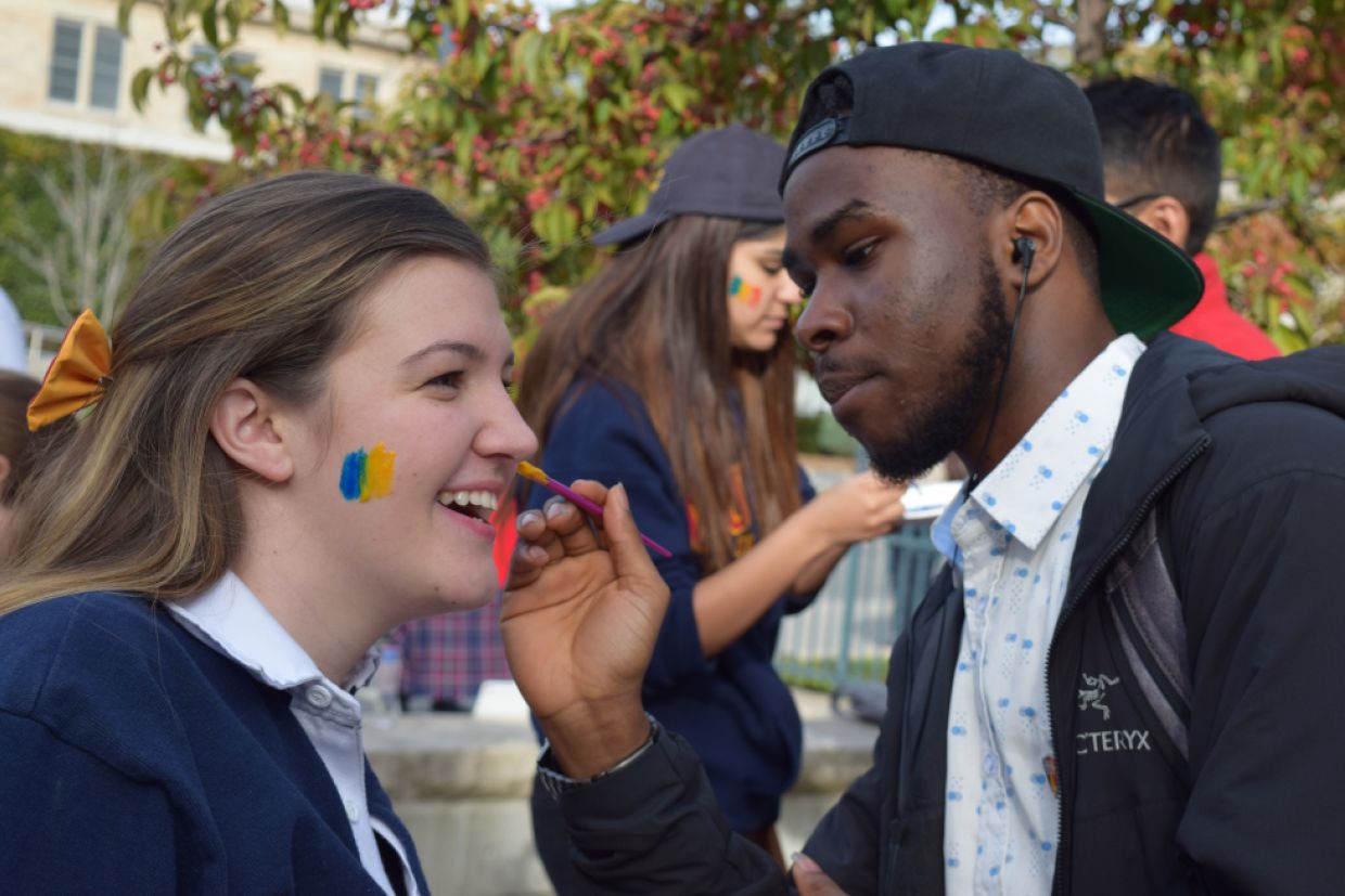 A QSAA member paints a tricolour flag on the cheek of a student.