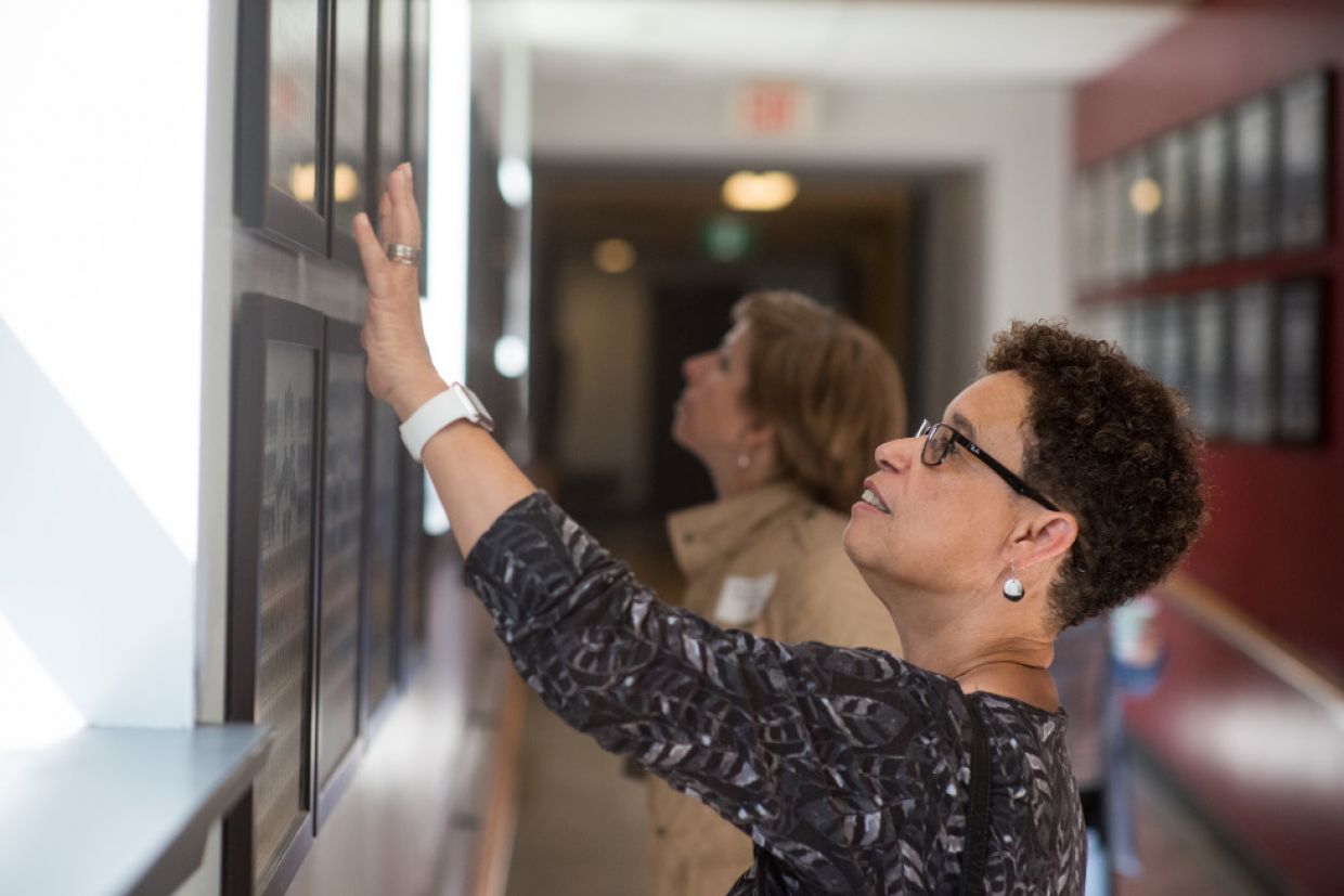 A person touches a plaque hanging on the wall of the Law Building. 