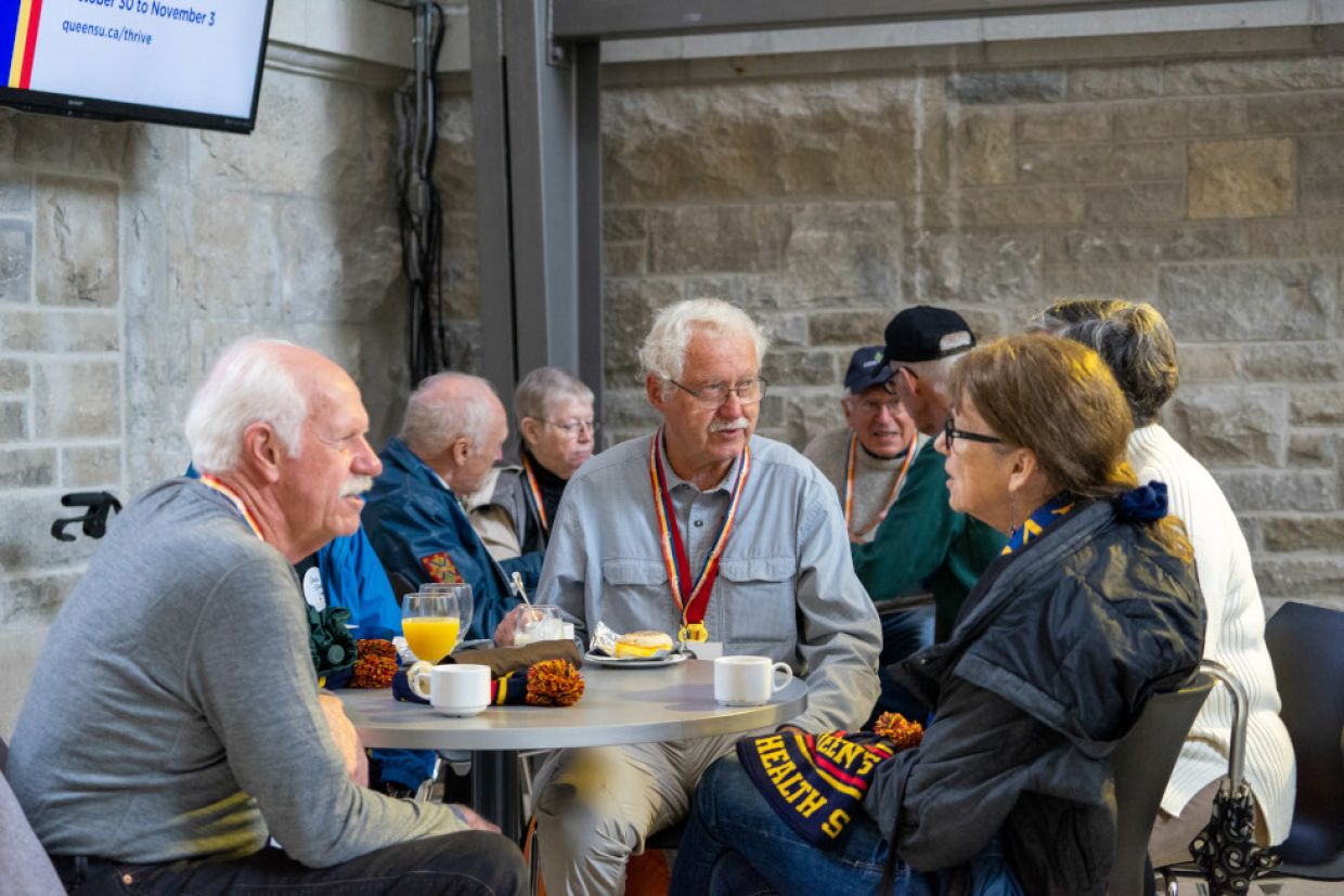 Alumni around table - People sit at a table engaged in conversation.