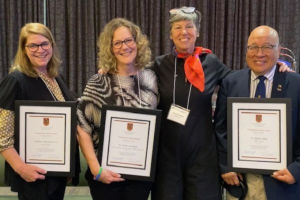 Recipients of the Distinguished Alumni Award hold plaques and pose for a photo.