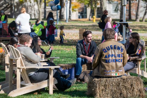 Five people sitting on chairs in a circle talking. 