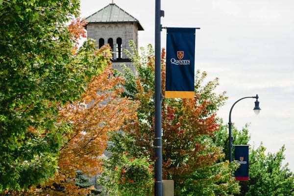 Queen's banner on lamp post with fall foliage nearby