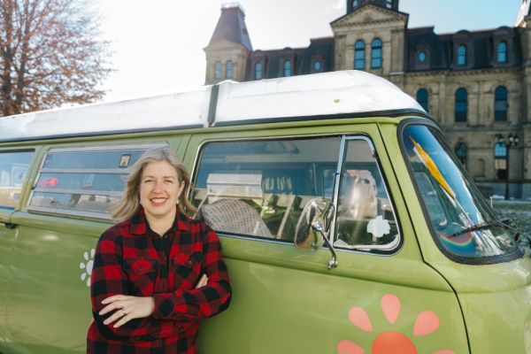 Susan Holt leans against a green van.