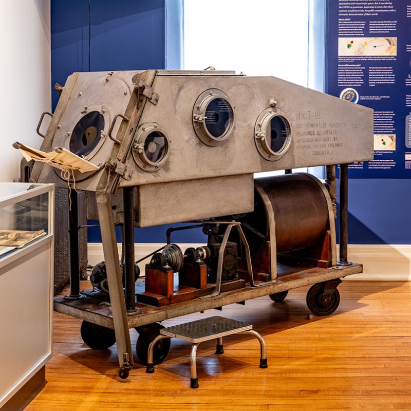 A large metal iron lung sits in the corner of a room. 