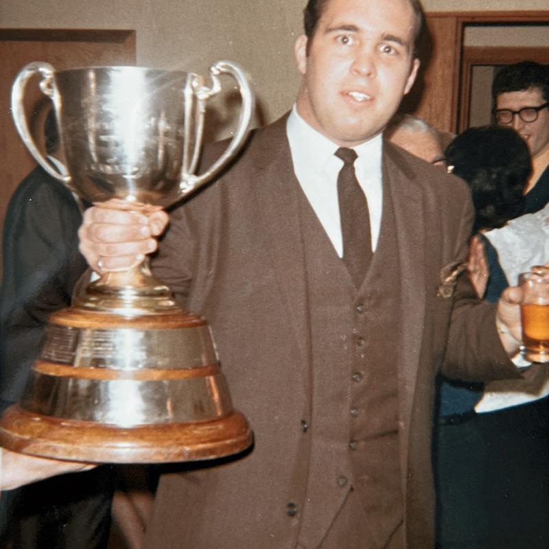 Thomas Beynon holding up a silver championship cup.