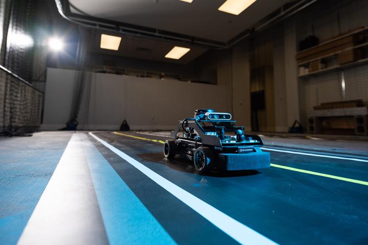A small car-like vehicle is on a track inside a room.