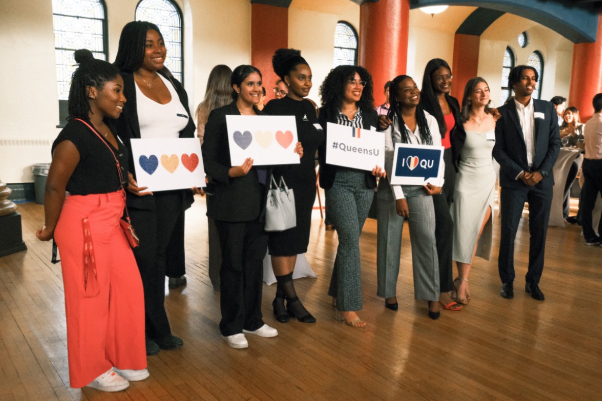 Major scholarship winners holding Queen's University signs in Grant Hall.