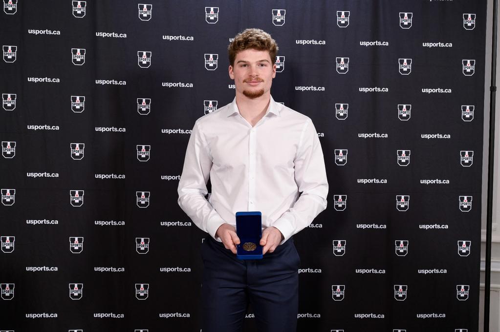 Ashton Miller-Melancon infront of a USports black backdrop.