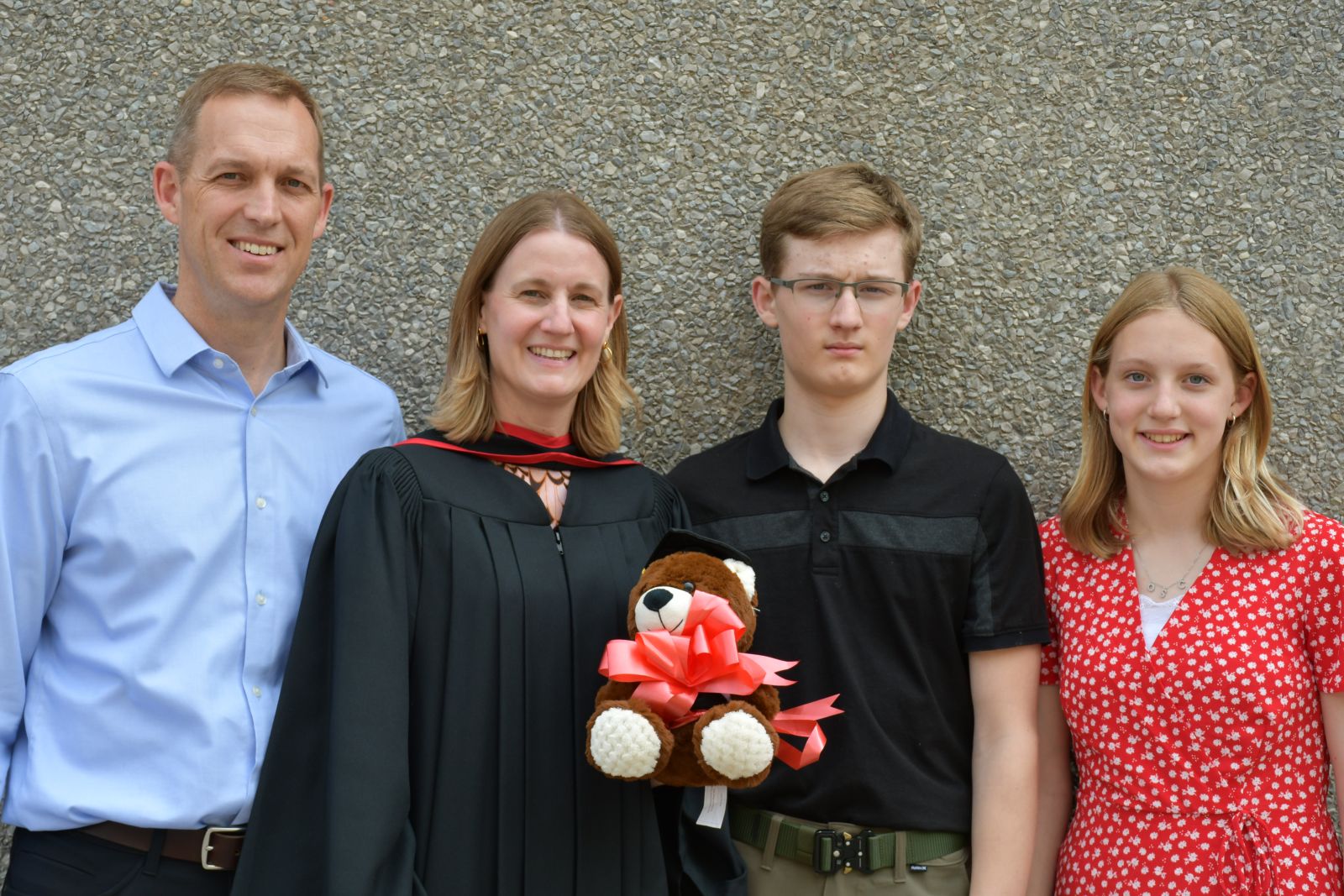 Graduating student and her family standing against a wall.