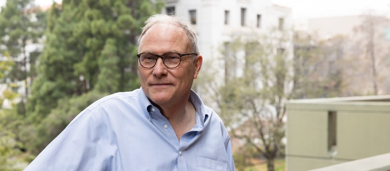 Dr. David E. Card standing outside.