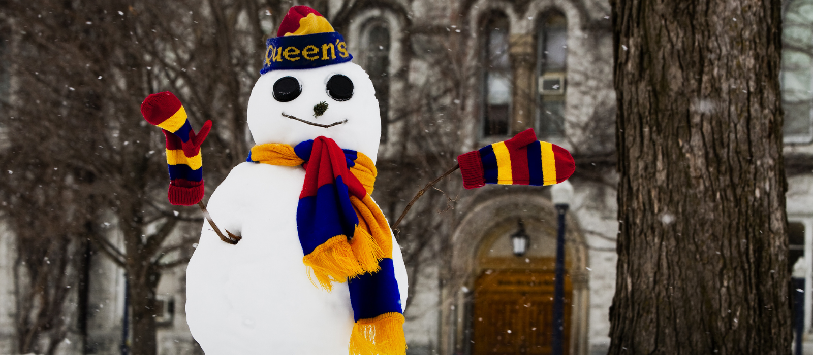 A snowman wearing a Queen's toque, mittens and scarf.