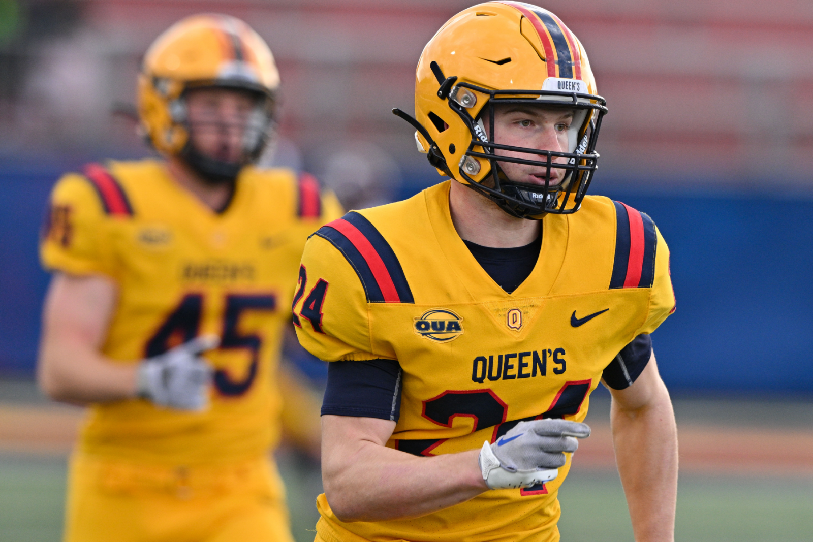 Ashton Miller-Millancon in Queen's yellow football uniform running on the field.