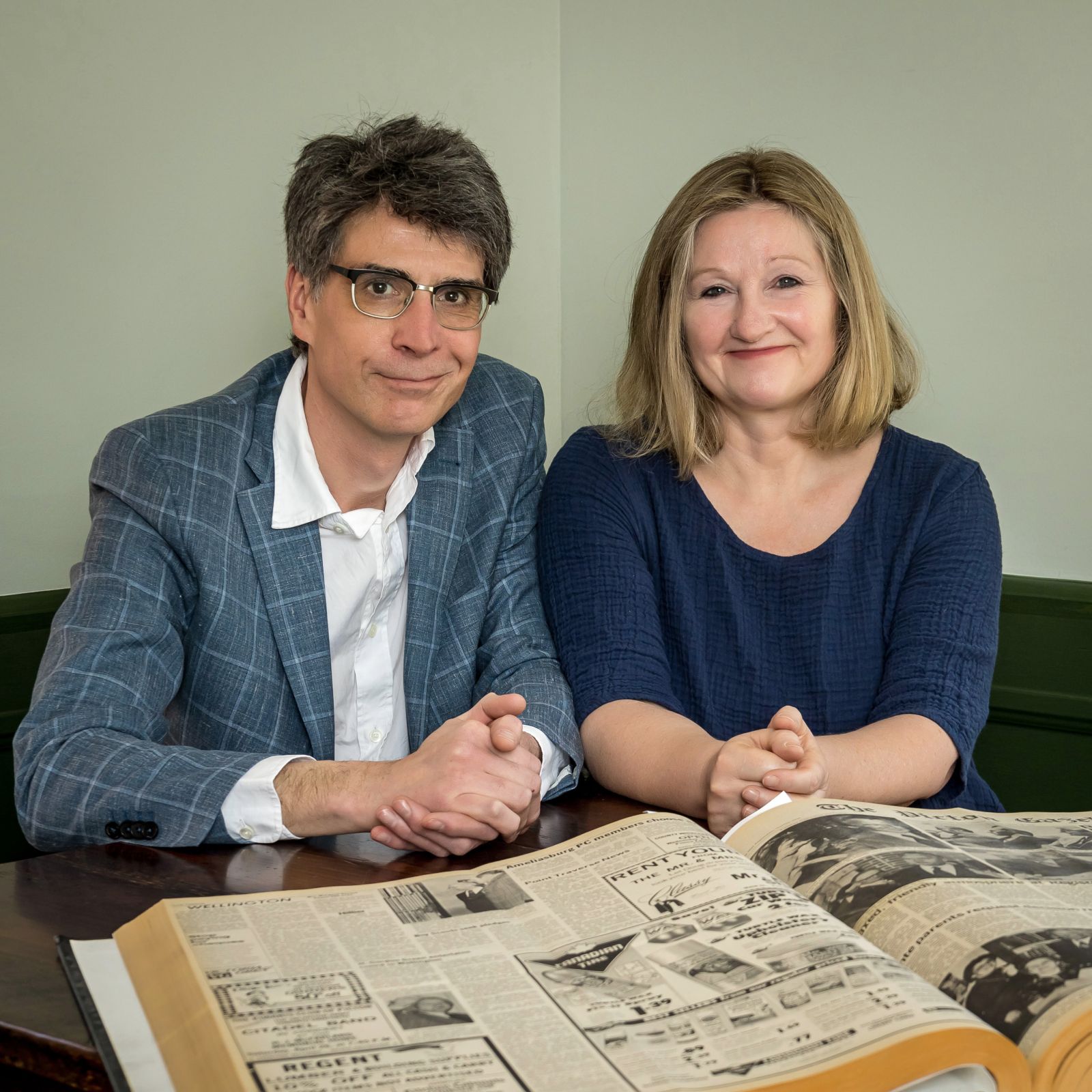 Chris Fanning and Karen Valihora sitting at a table with a newspaper in front of them.