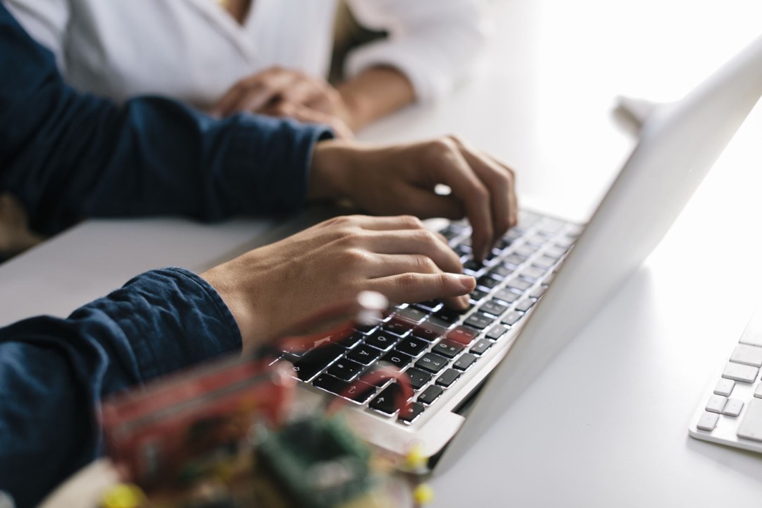 person working on a laptop with a person beside them