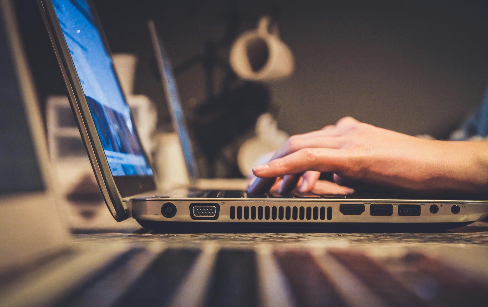 person with their hands above a laptop