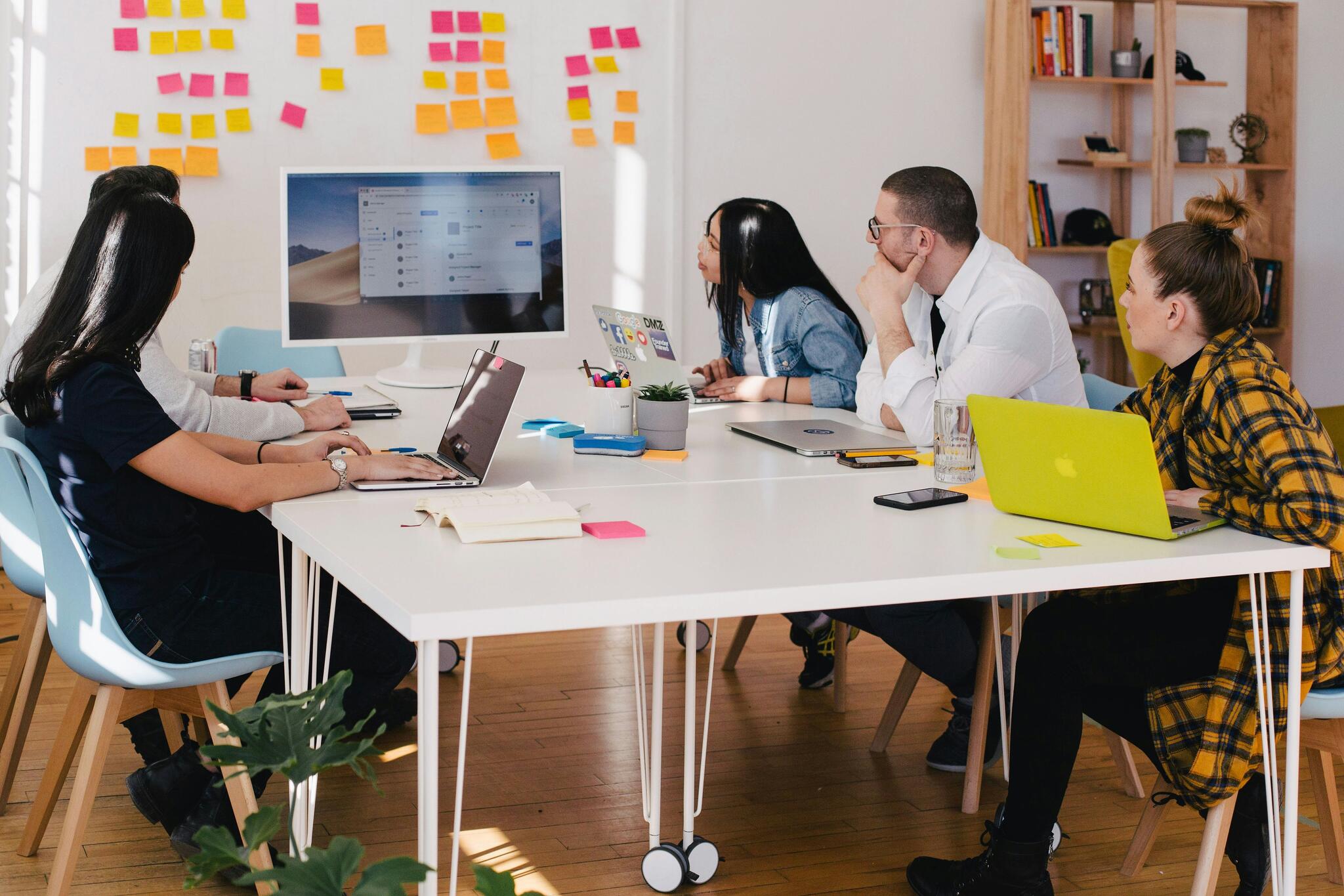 people working around a communal table looking at a screen