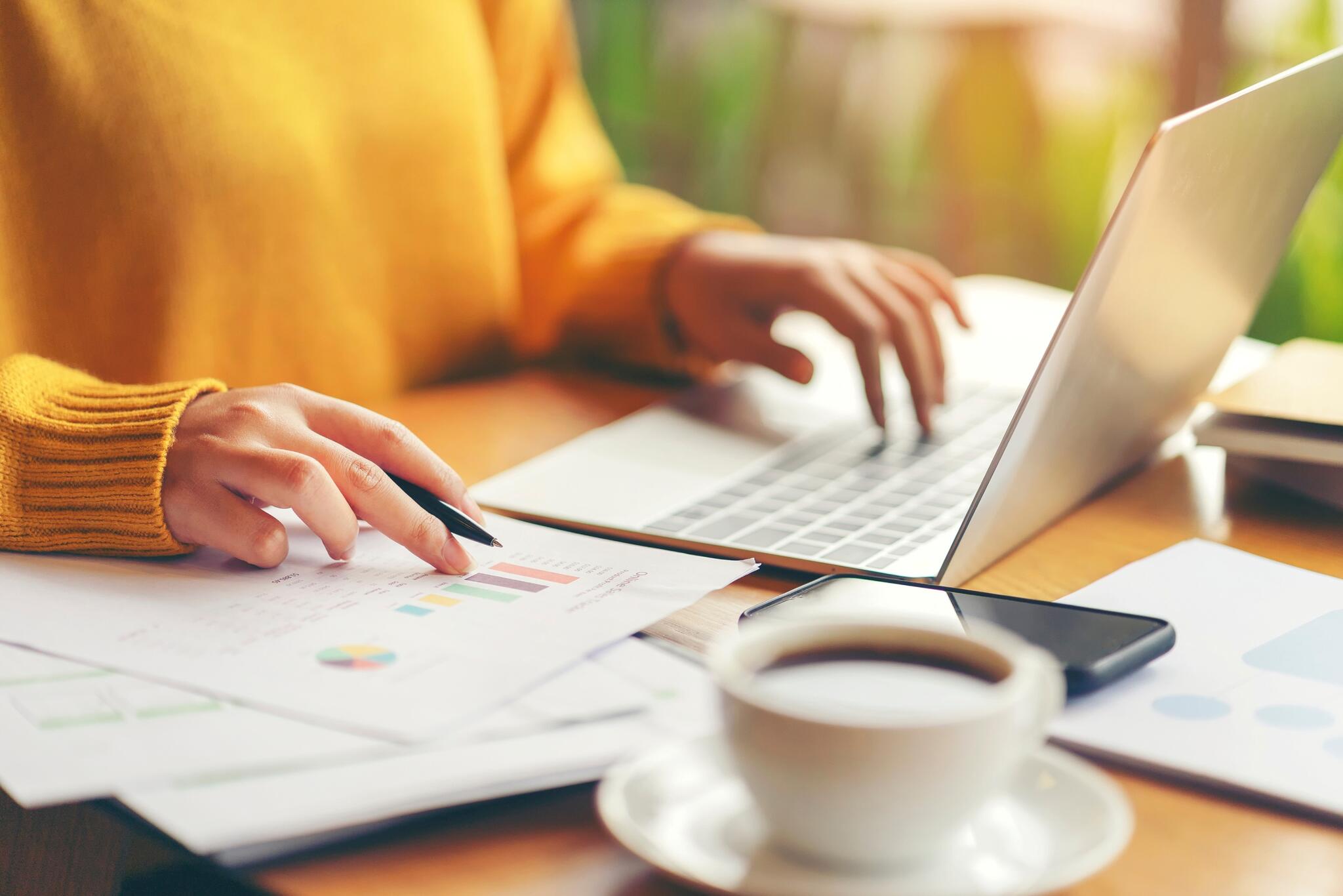 woman sitting at a computer with documents beside her