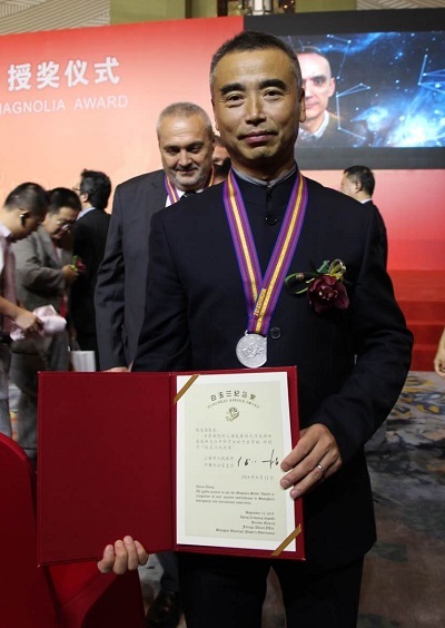 [Dr. Zhang poses with his award.]