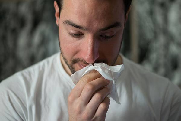 A man wipes his nose with a tissue