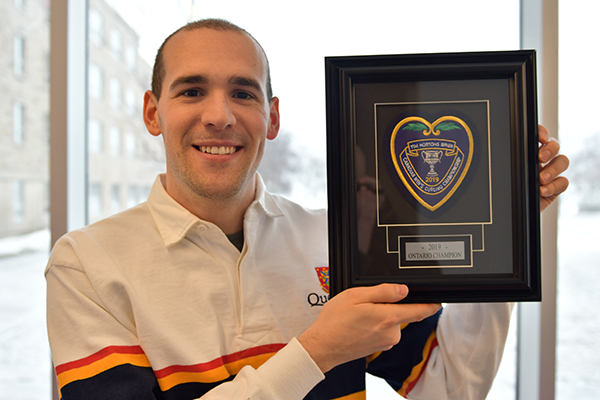 [Wesley Forget holds up the purple heart he received for winning the Ontario Curling Championship.]